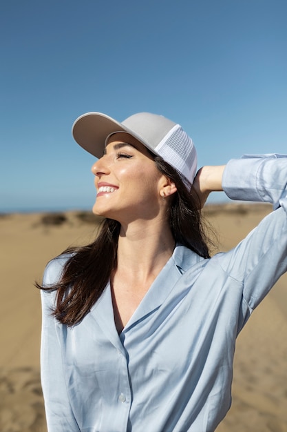 Donna sorridente del colpo medio che posa con il cappello del camionista