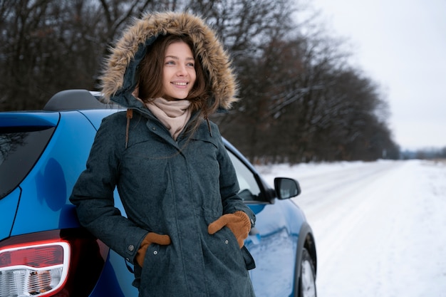 Donna sorridente del colpo medio che sta vicino all'automobile