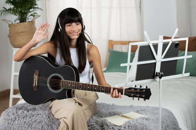 Donna sorridente del colpo medio che suona la chitarra