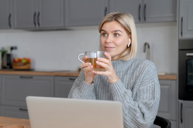 Donna sorridente del colpo medio che tiene tazza di tè