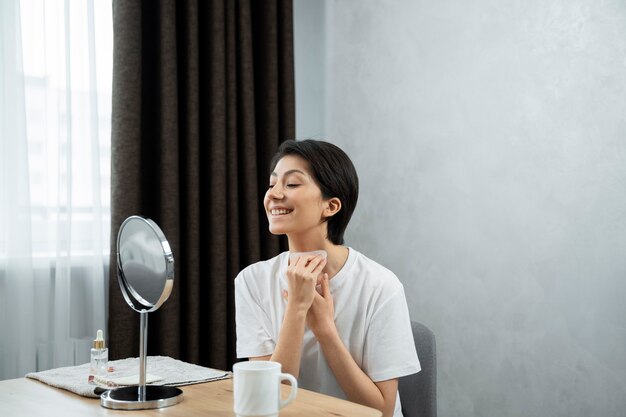 Donna sorridente del colpo medio che utilizza lo strumento del viso