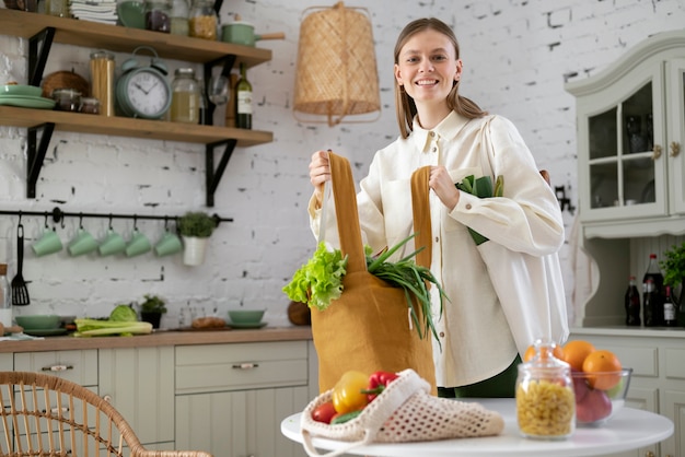 Donna sorridente del colpo medio con generi alimentari