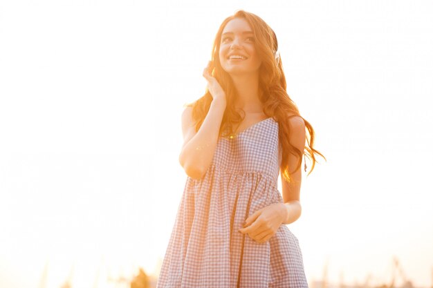 Donna sorridente dello zenzero di bellezza nella musica d'ascolto del vestito