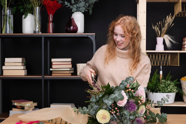 Donna sorridente di colpo medio al negozio di fiori
