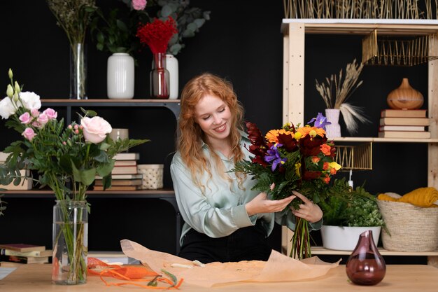 Donna sorridente di colpo medio al negozio di fiori