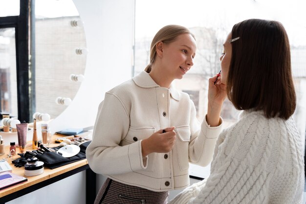 Donna sorridente di colpo medio che fa trucco