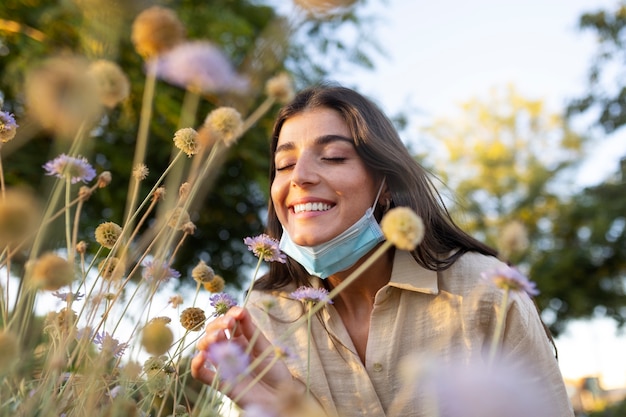 Donna sorridente di colpo medio che odora di fiori