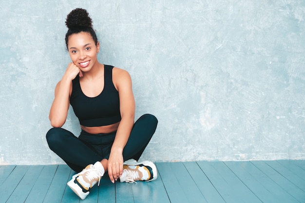 Donna sorridente di forma fisica in abbigliamento sportivo con l'acconciatura di riccioli afro