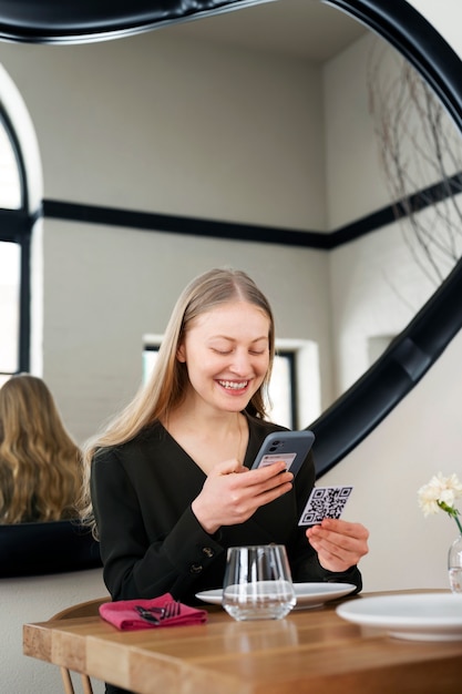 Donna sorridente di scatto medio che scansiona qr