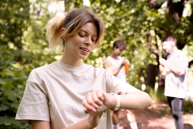 Donna sorridente di vista laterale che controlla il suo orologio