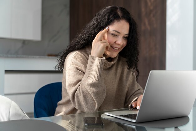 Donna sorridente di vista laterale che lavora al computer portatile