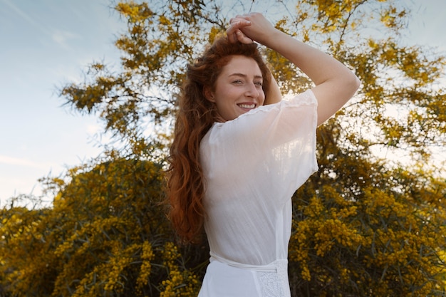 Donna sorridente di vista laterale che posa all'aperto