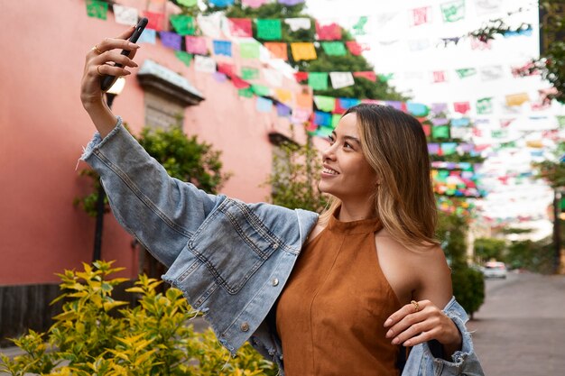 Donna sorridente di vista laterale che prende selfie all'aperto