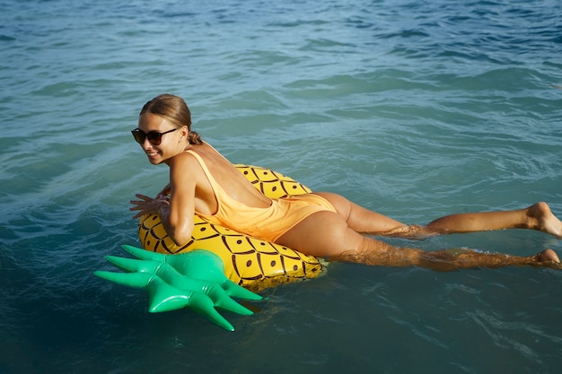 Donna sorridente di vista laterale sul galleggiante dell'ananas