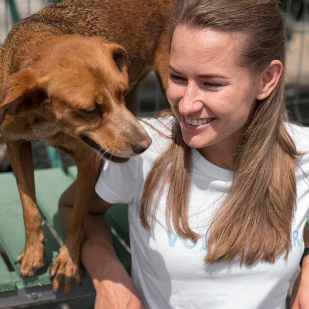 Donna sorridente e simpatico cane da salvataggio al rifugio