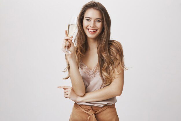Donna sorridente felice che beve champagne alla festa