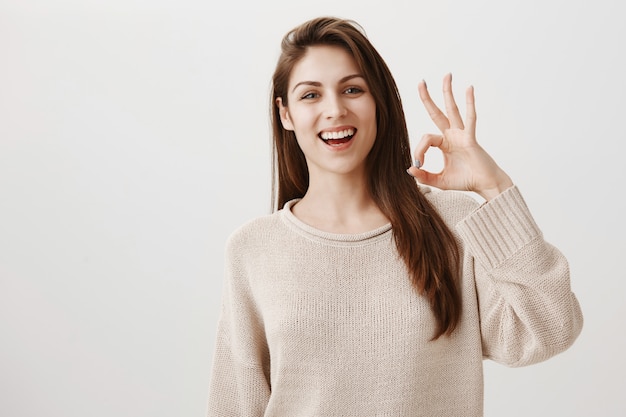 Donna sorridente felice che mostra il gesto giusto soddisfatto, approvare o raccomandare il prodotto