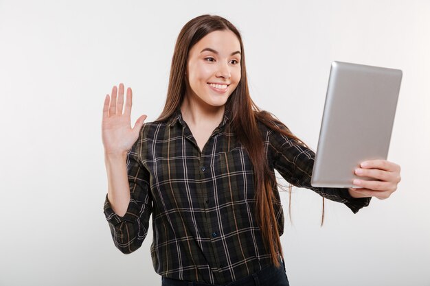 Donna sorridente in camicia che fa selfie sul computer tablet