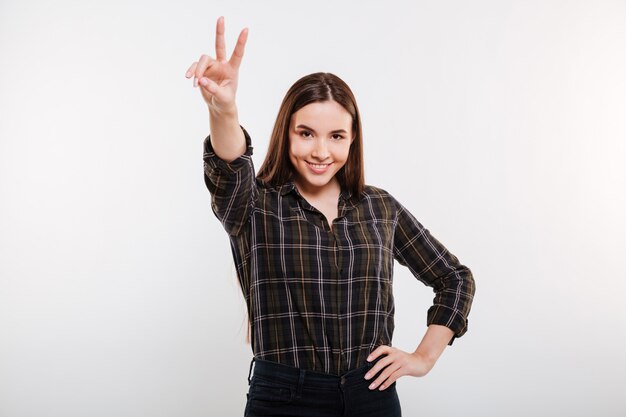 Donna sorridente in camicia che mostra il segno di pace