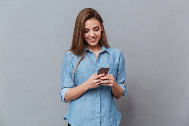 Donna sorridente in camicia usando il telefono