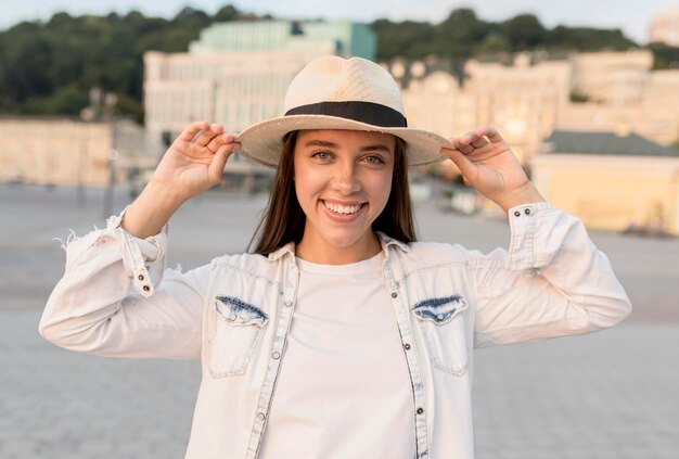 Donna sorridente in posa all'aperto con il cappello durante il viaggio