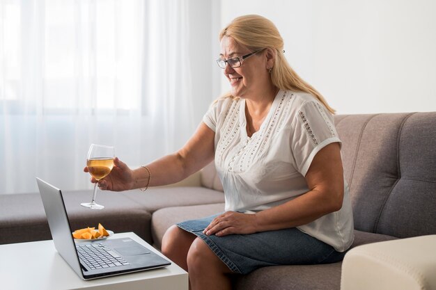 Donna sorridente in quarantena con un drink con il computer portatile