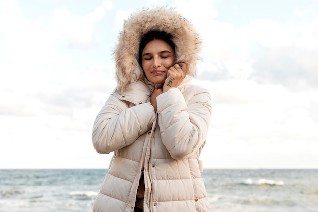 Donna sorridente in spiaggia con giacca invernale