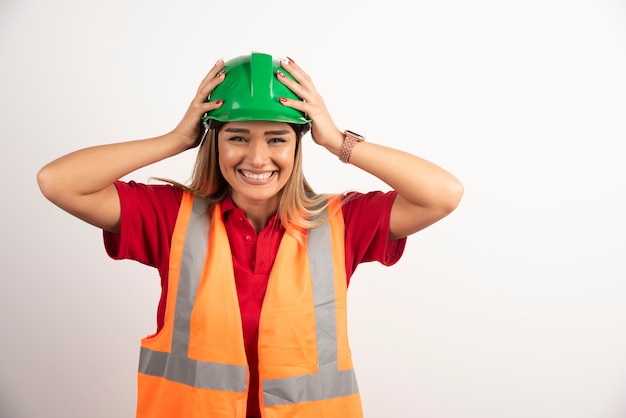 Donna sorridente in uniforme protettiva e casco in posa su sfondo bianco.