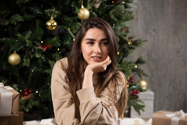 Donna sorridente sdraiata su soffice tappeto con regali di Natale.