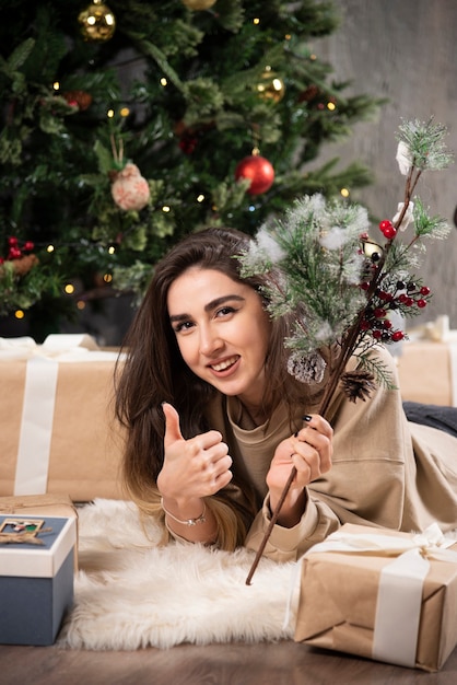 Donna sorridente sdraiata sul soffice tappeto che mostra un pollice in su.