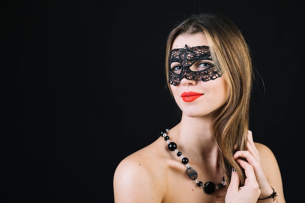 Donna sorridente splendida nella maschera di carnevale di travestimento sul contesto nero