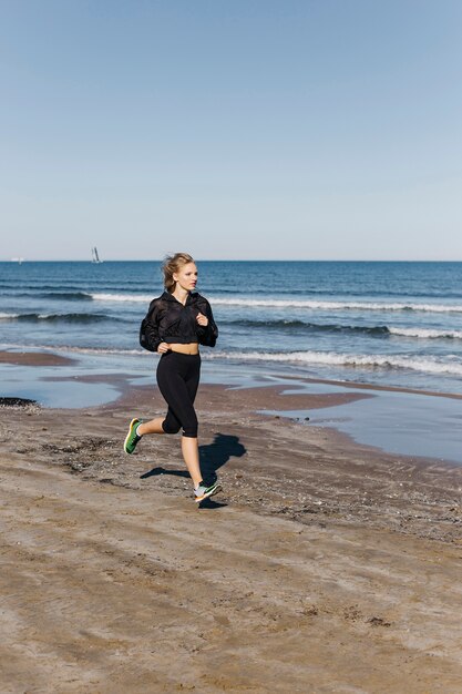 Donna sportiva che corre in spiaggia