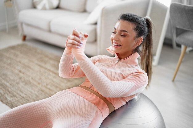 Donna sportiva che fa esercizi addominali sulla palla fitness a casa