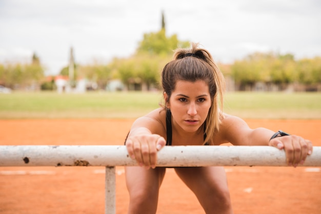 Donna sportiva che si estende sulla pista dello stadio