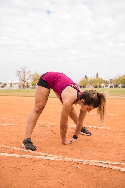 Donna sportiva che si estende sulla pista dello stadio