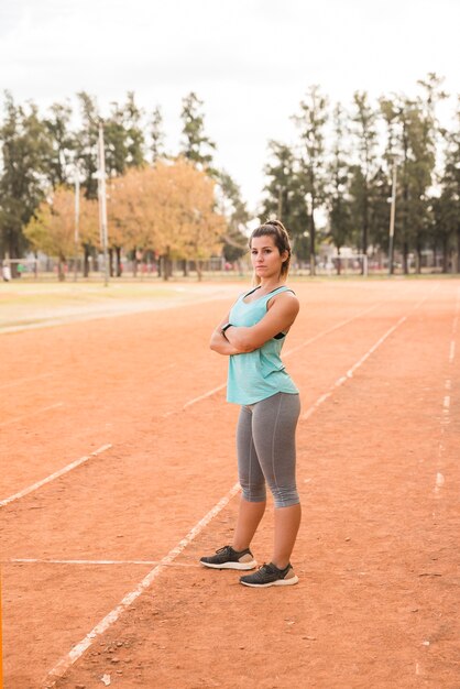 Donna sportiva che si estende sulla pista dello stadio