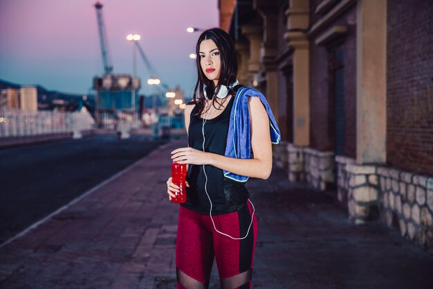 Donna sportiva con la bottiglia che guarda l&#39;obbiettivo