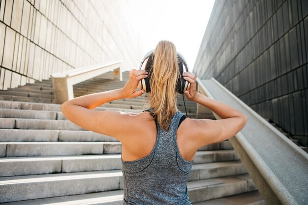 Donna sportiva con le cuffie nell&#39;ambiente urbano