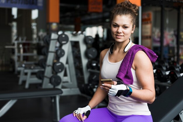 Donna sportiva con lo smartphone che guarda l&#39;obbiettivo