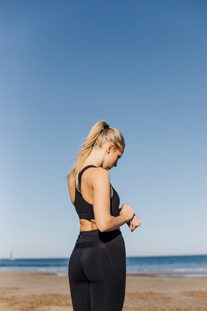 Donna sportiva con smartwatch in spiaggia