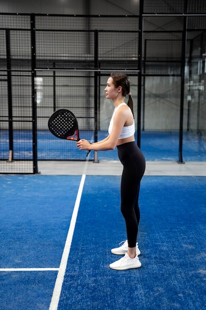 Donna sportiva del colpo pieno che gioca a paddle tennis