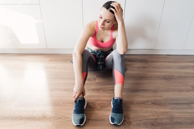 Donna sportiva del ritratto che riposa dopo l'allenamento a casa