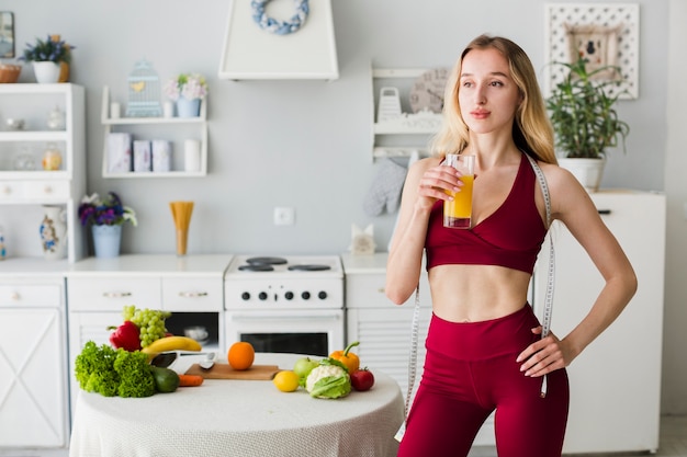 Donna sportiva in cucina con succo sano