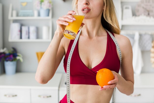 Donna sportiva in cucina con succo sano