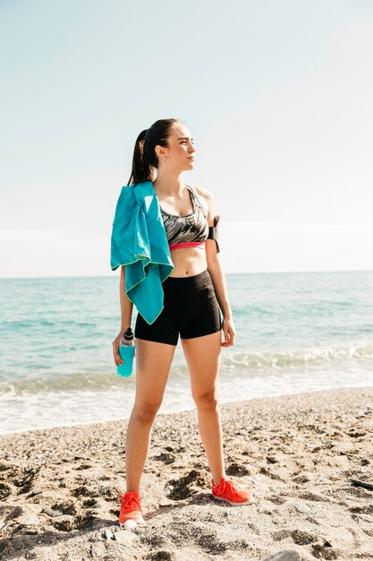 Donna sportiva in piedi sulla spiaggia