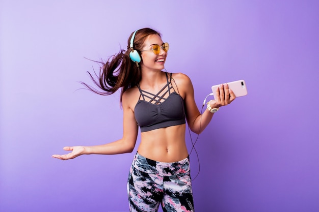 Donna sportiva spensierata che gioca con i capelli e che fa autoritratto dal telefono cellulare durante l'allenamento. Indossa un reggiseno elegante.