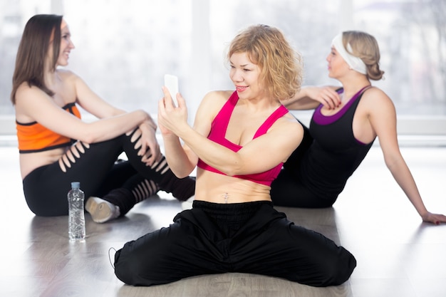 Donna sportiva utilizzando smartphone in pausa in classe di fitness