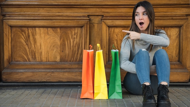 Donna stupita che si siede vicino a pacchetti commerciali