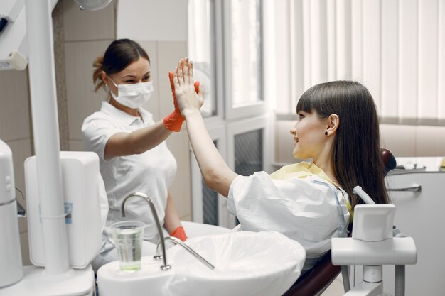 Donna su una poltrona odontoiatrica. La ragazza viene esaminata da un dentista Il medico dà cinque pazienti