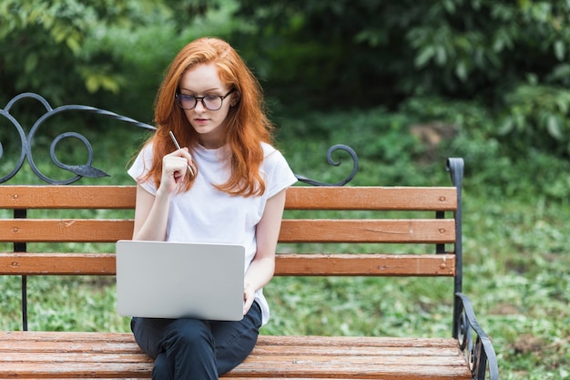 Donna sul banco di legno con laptop e penna